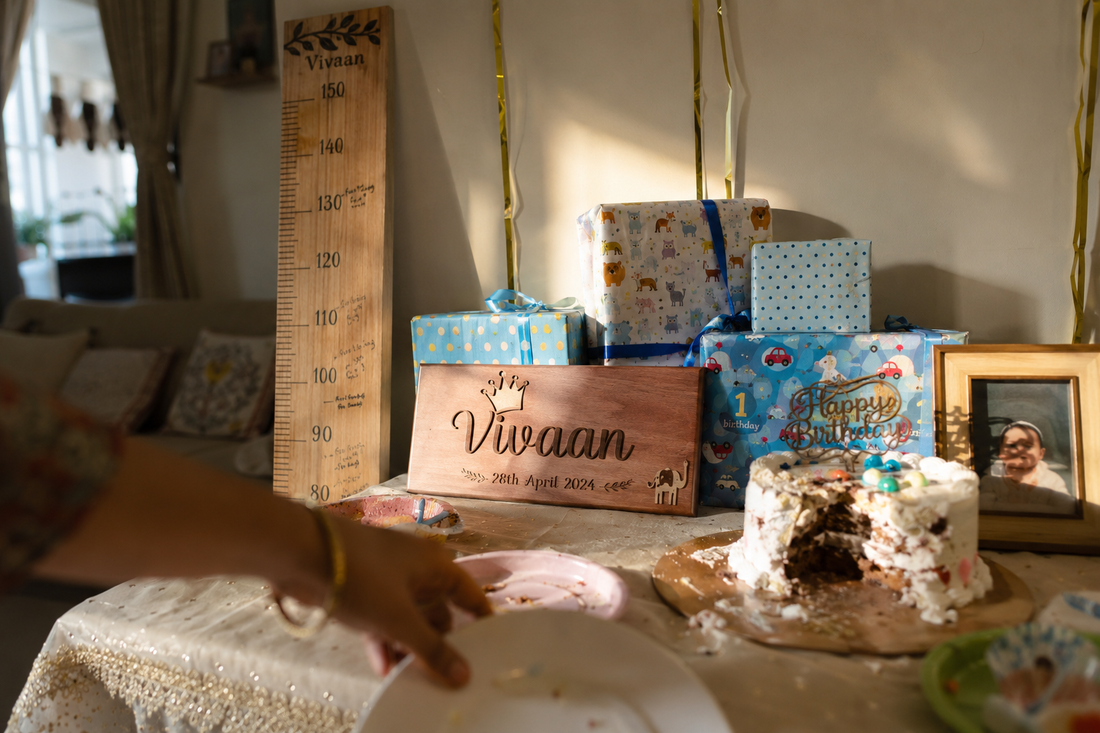 First birthday party table in an Indian home with a smash cake, wooden height chart, and personalized wooden nameplate on display