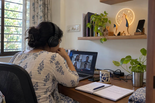 Woman on a video call at her home desk with the Lone Wolf wooden table lamp on a shelf behind her