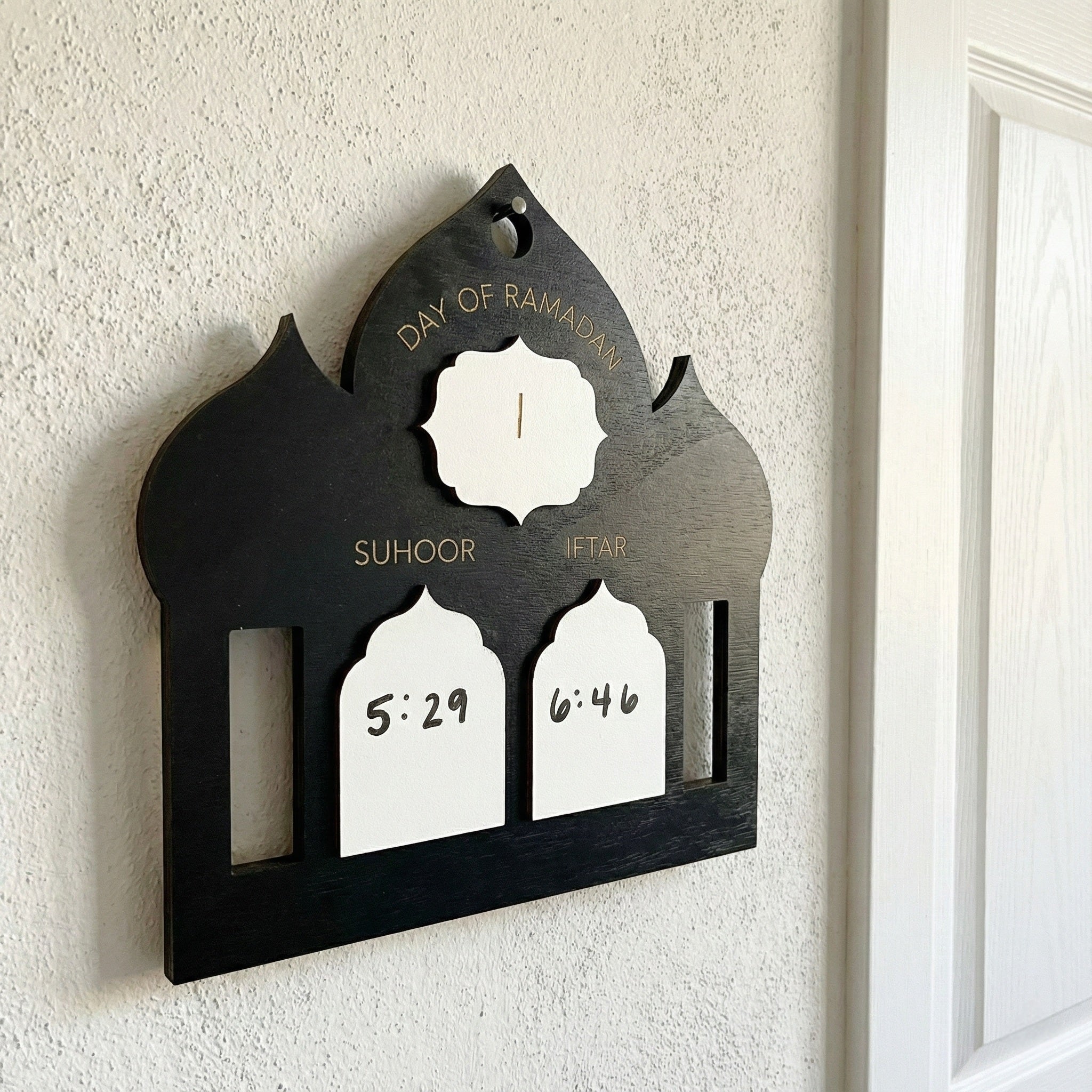 Decorative wall hanging with clock and time markers on a white wall