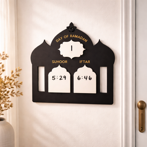 Wall-mounted device displaying 'Day of Ramadan' times for Suhoor and Iftar on a white wall.