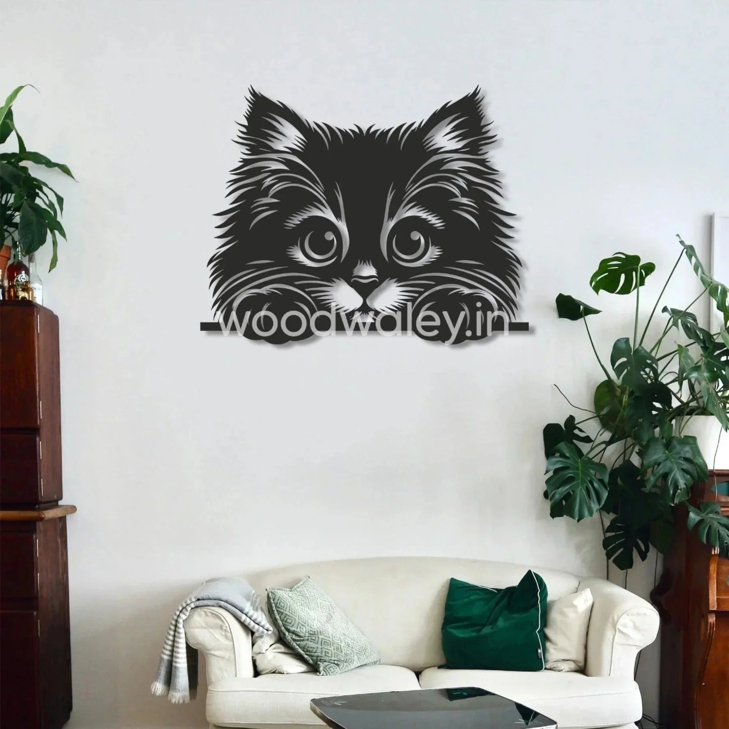 Black wooden cat wall art above a modern sofa with green plants in a cozy living room