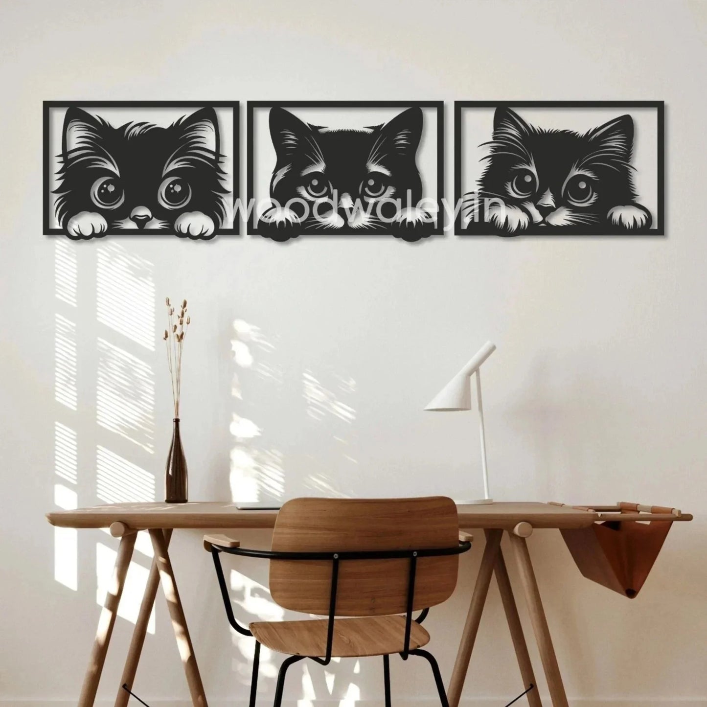 Set of three black wooden cat wall art frames above minimalist wooden desk